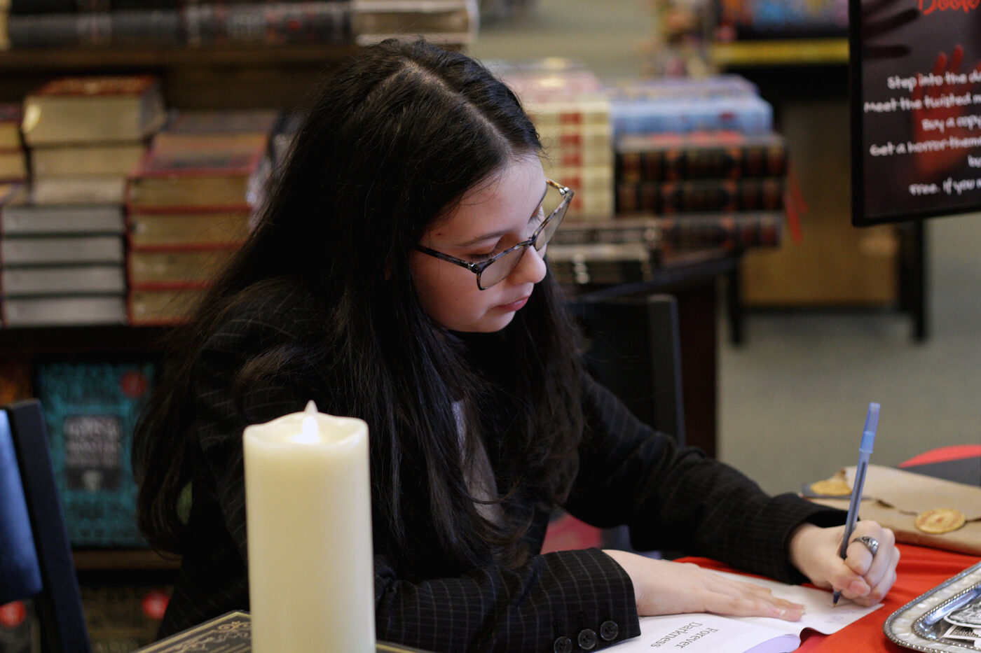 Ma'ayan signing a copy of Forever Darkness by candlelight