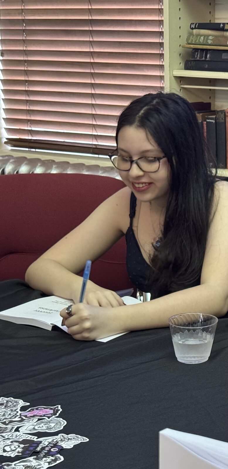 Ma'ayan Harel-Sibelman smiling while signing a copy of Forever Darkness